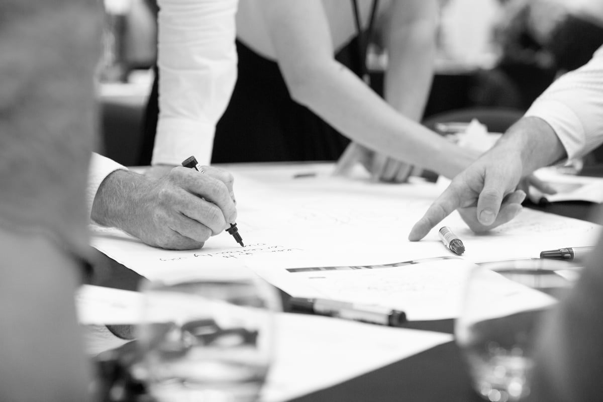 Person writing in a workshop, with another person pointing