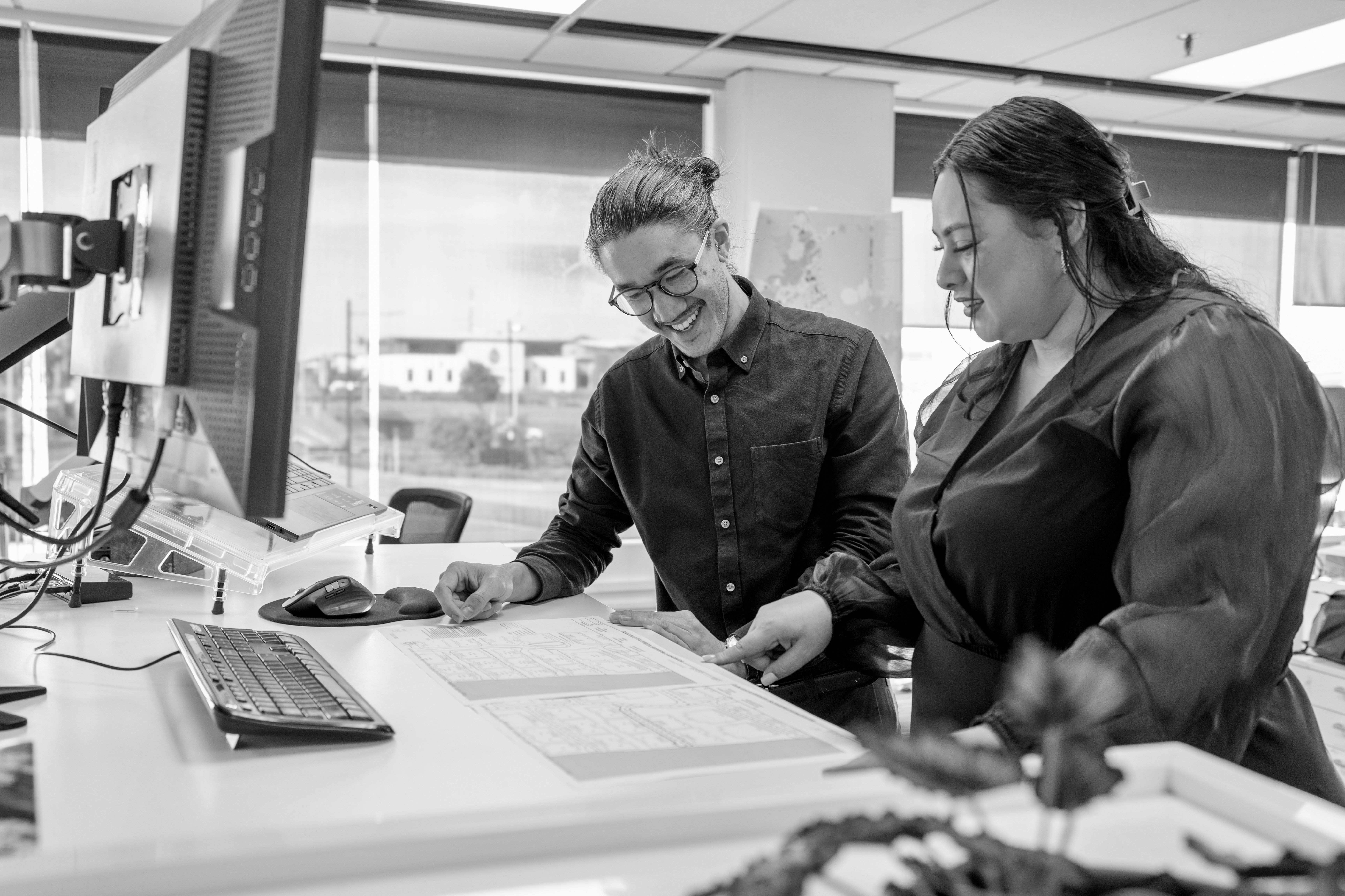Two people working at a stand up desk in front of a computer